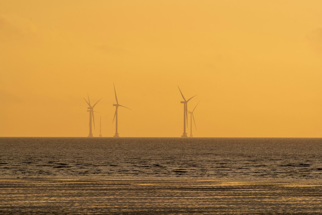 Offshore wind turbines standing in the ocean at sunset